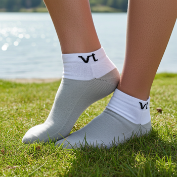 Infrared white socks with VT logo worn by a person on grass with a lake in the background