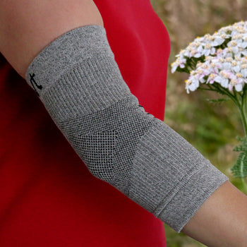 Grey Elbow Sleeve/Brace on a Woman’s Arm with a Natural Background
