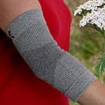 Grey Elbow Sleeve/Brace on a Woman’s Arm with a Natural Background